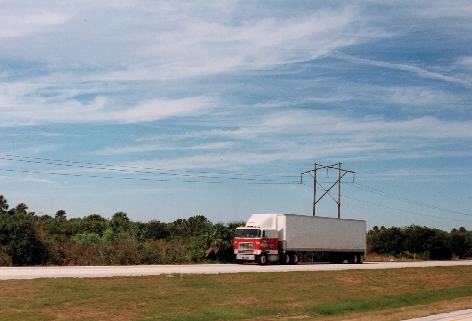 A tractor trailer travelling along an open highway under a wide sky